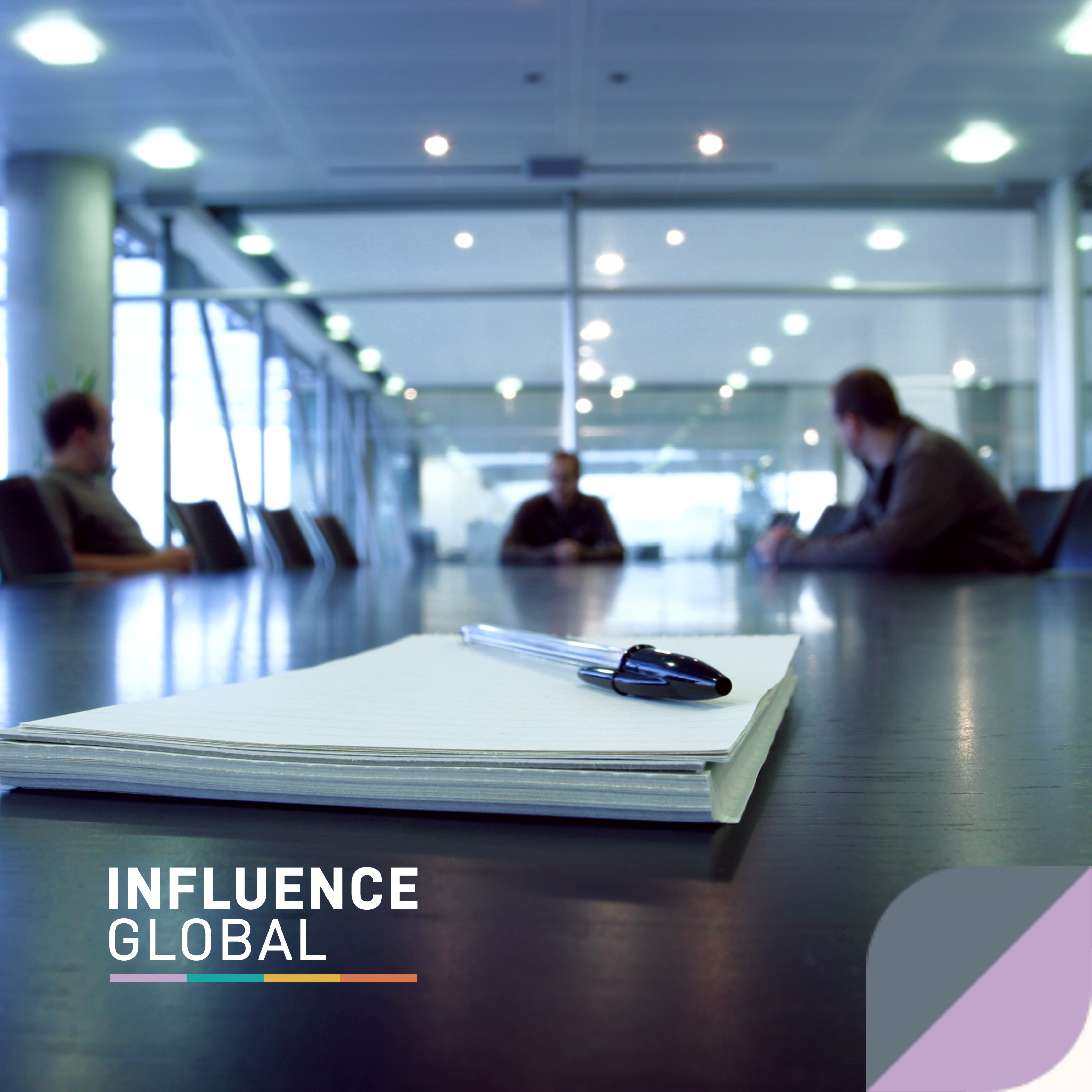 A photo of a pile of papers and pen on a large Boardroom desk. People are in the room at the back but are blurred in the photo. Influence Global logo is in the bottomleft corner and a page-turn tab (grey and purple colour) is on the right.